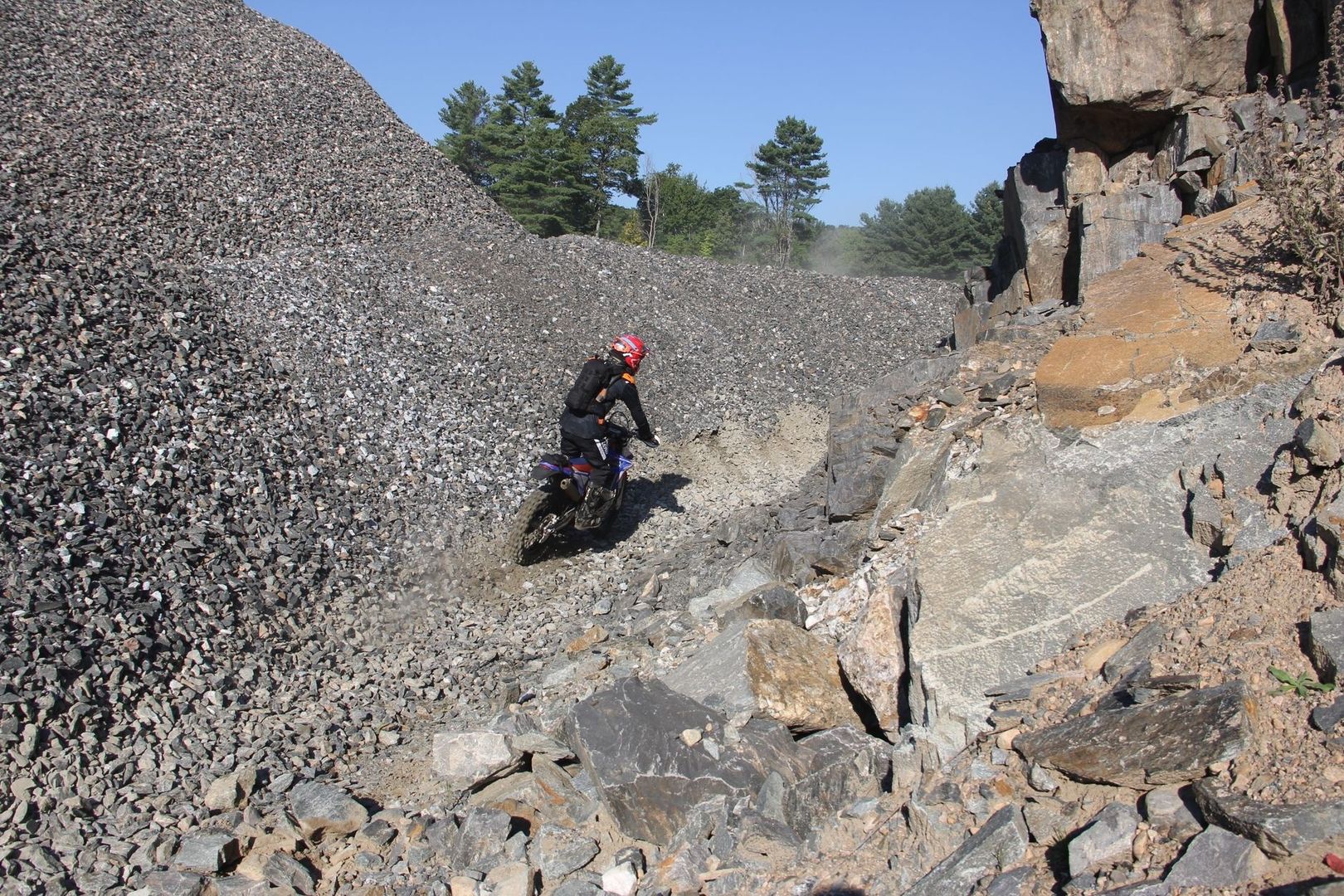 Motorcyclist navigating a rocky, steep off-camber mountain trail